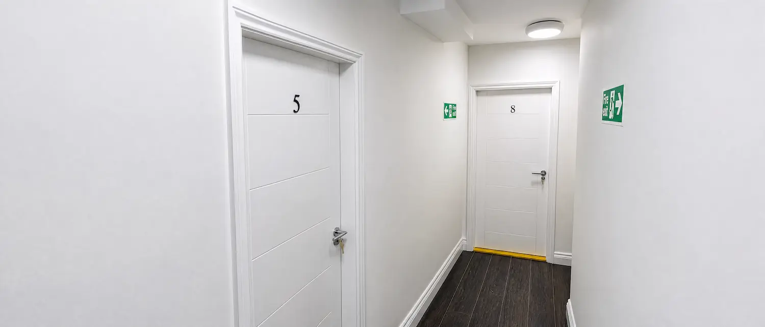 White flat entrance fire doors with dark timber flooring in Milton Keynes
